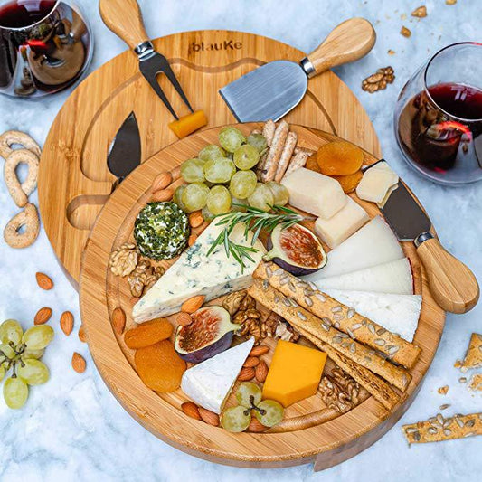 Wooden charcuterie board with assorted cheeses, fruits, and nuts on a marble surface.