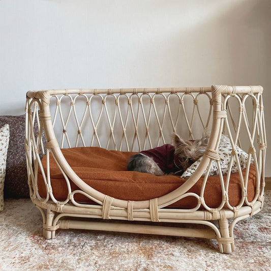 Wicker pet bed with a dog inside on a textured floor.